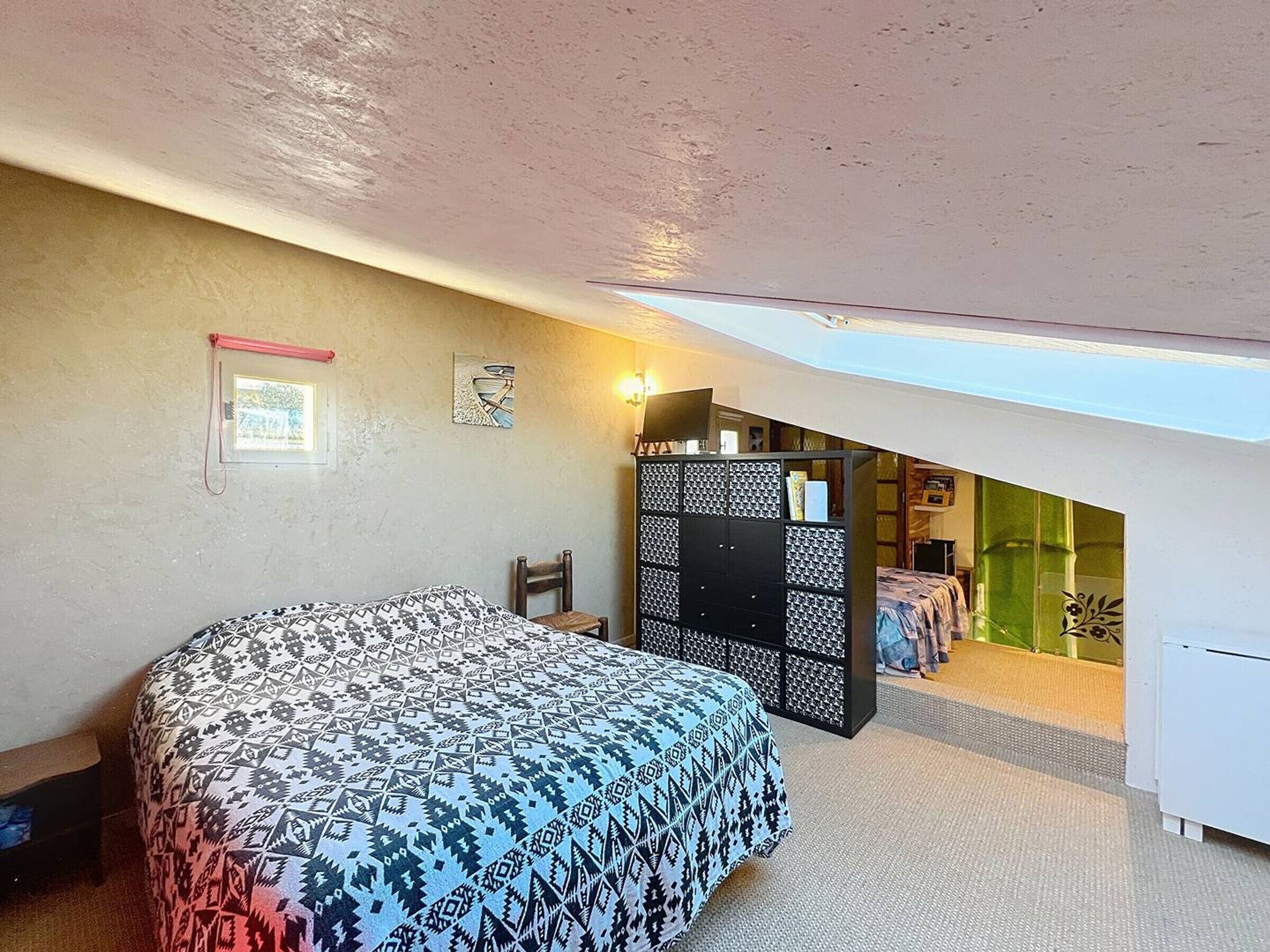Een slaapkamer met een bed, een stoel, een kledingkast en een dakvenster.