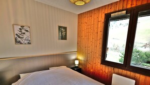 Camera da letto con un letto grande, pareti in pannelli di legno, una finestra con vista e due opere d'arte appese al muro.