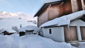 Un chalet di legno con tetto imbiancato dalla neve, sullo sfondo di montagne innevate.