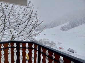 A snowy landscape with a snow-covered tree in the foreground and a snow-covered road in the background. - Bright studio with balcony, mountain view, 25m² (Le Biot)