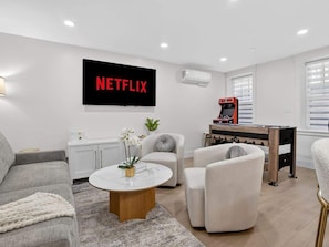 Una sala de estar moderna con un televisor de pantalla plana, una mesa de fútbol de mesa y un sofá.