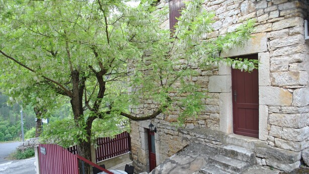 Un edificio de piedra con puerta roja y un pequeño porche.