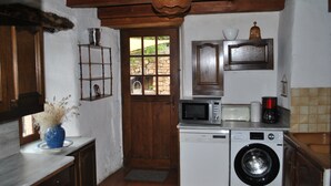 Una cocina funcional equipada con lavadora, microondas y cafetera.