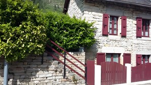 A stone building with red shutters and a metal staircase. - Gîte “Le Vignou” in Ste-Enimie: Mountain View, Private Terrace, and Wi-Fi (Gorges du Tarn Causses)