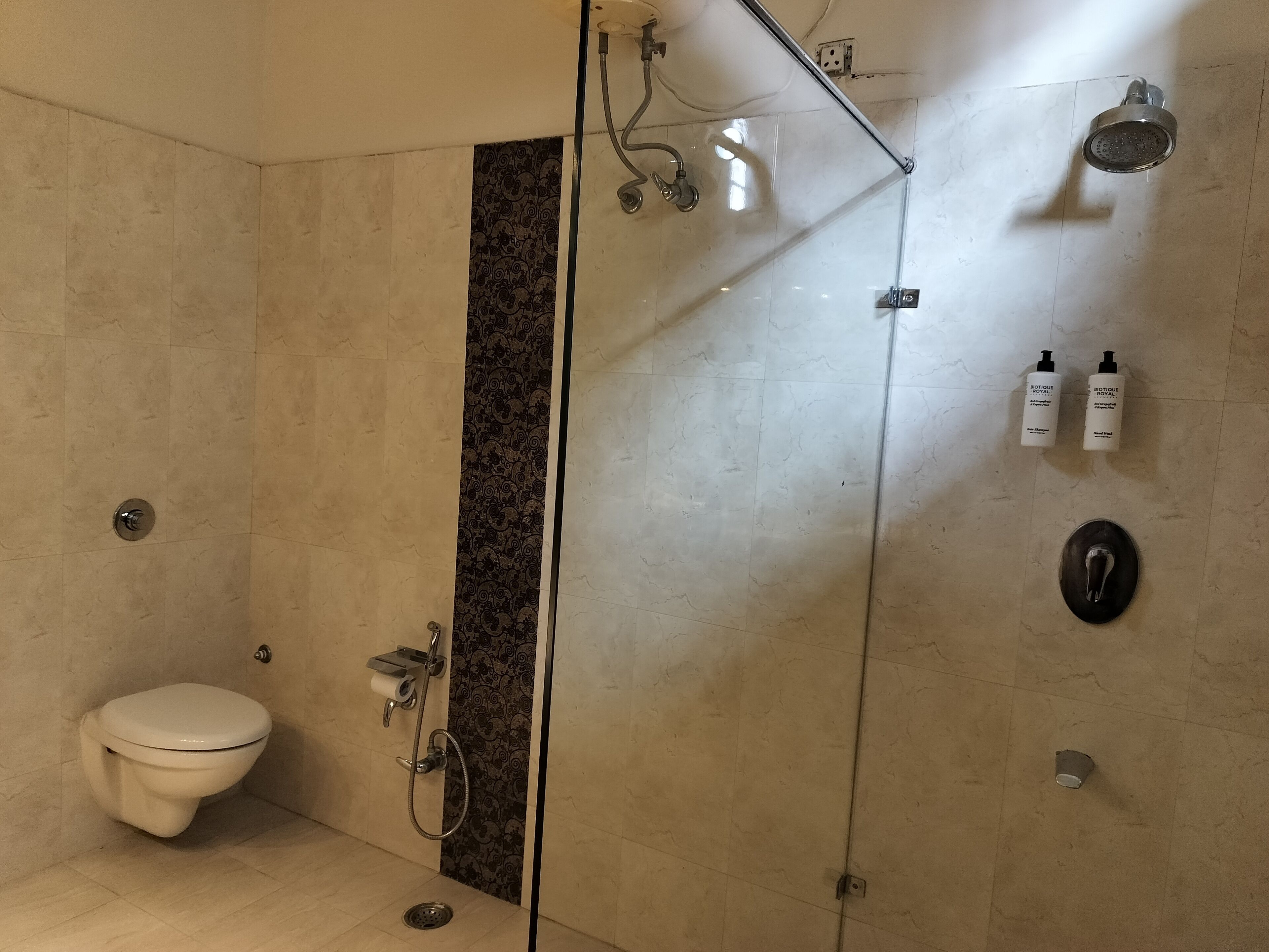Un baño con inodoro, cabina de ducha y dos botellas de artículos de tocador en la pared.