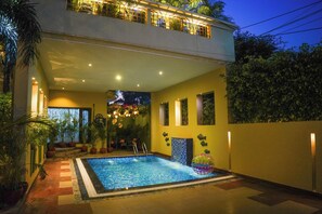 Ein modernes Haus mit Swimmingpool, Balkon und Topfpflanzen.