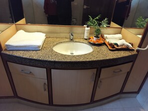 Ein Badezimmer mit Granitwaschtisch, einem weißen Waschbecken und Holzschränken.