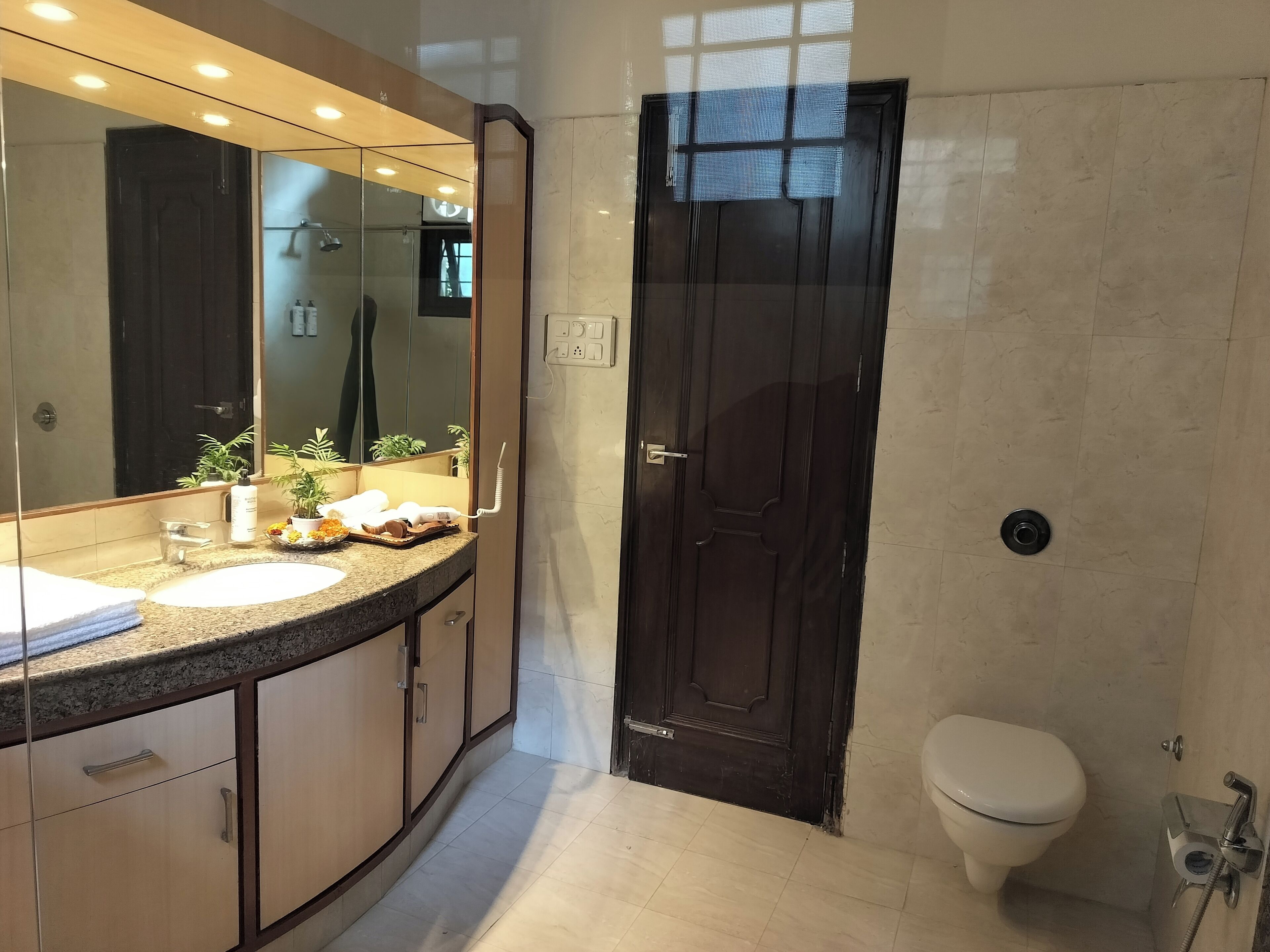 Un baño moderno con un espejo grande, dos lavamanos, un inodoro y una ducha.