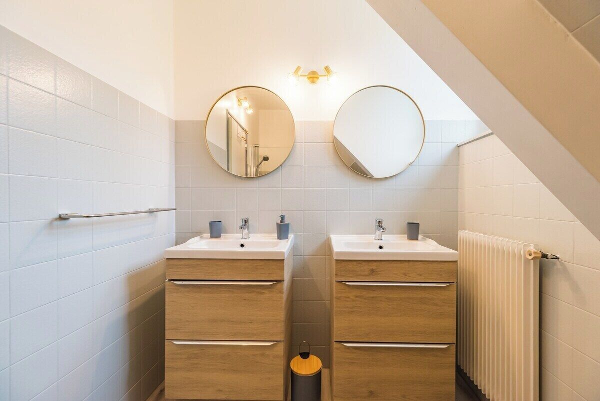 A modern bathroom with two sinks, wooden cabinets, and a towel rack.