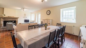 Een ruime woonkamer met een open haard, een eettafel en een gezellige zithoek.