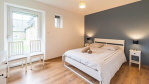 Een slaapkamer met een bed, twee nachtkastjes, een raam en een stoel.