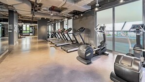 A gym with treadmills, elliptical machines, and weight benches. - Stylish 2BR with Beach Access (Dubai)