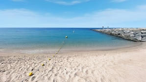 A sandy beach with a clear blue sky and calm sea. - Stylish 2BR with Beach Access (Dubai)