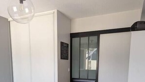A bedroom with a bed, a wardrobe, a sliding door, and a hanging light fixture. - Seaside apartment – Perros-Guirec (Perros-Guirec)