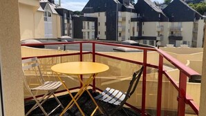 A balcony with a yellow table and two chairs, overlooking a residential area with houses. - Seaside apartment – Perros-Guirec (Perros-Guirec)