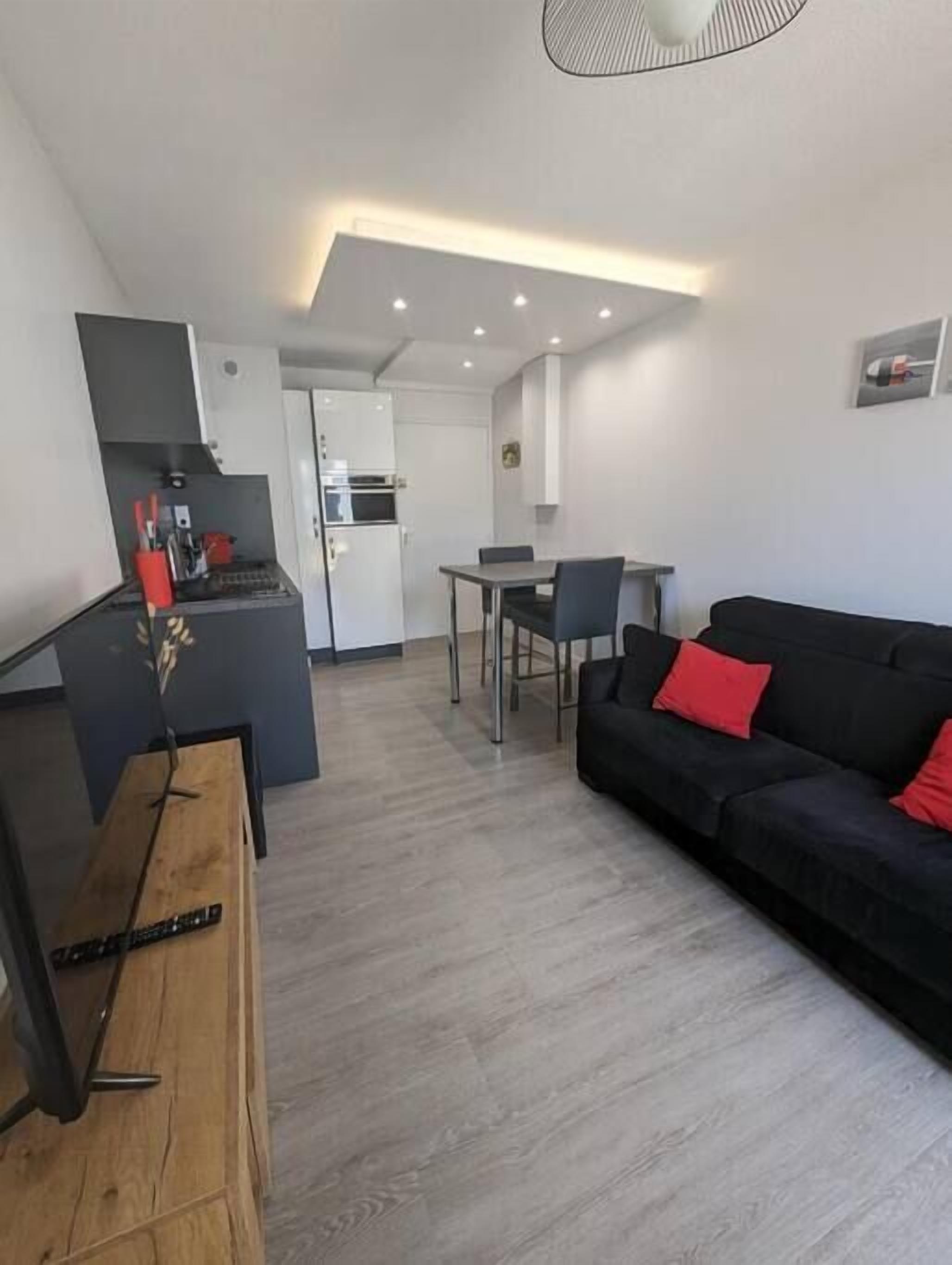 Un espacio habitable compacto con kitchenette, comedor y sofá.