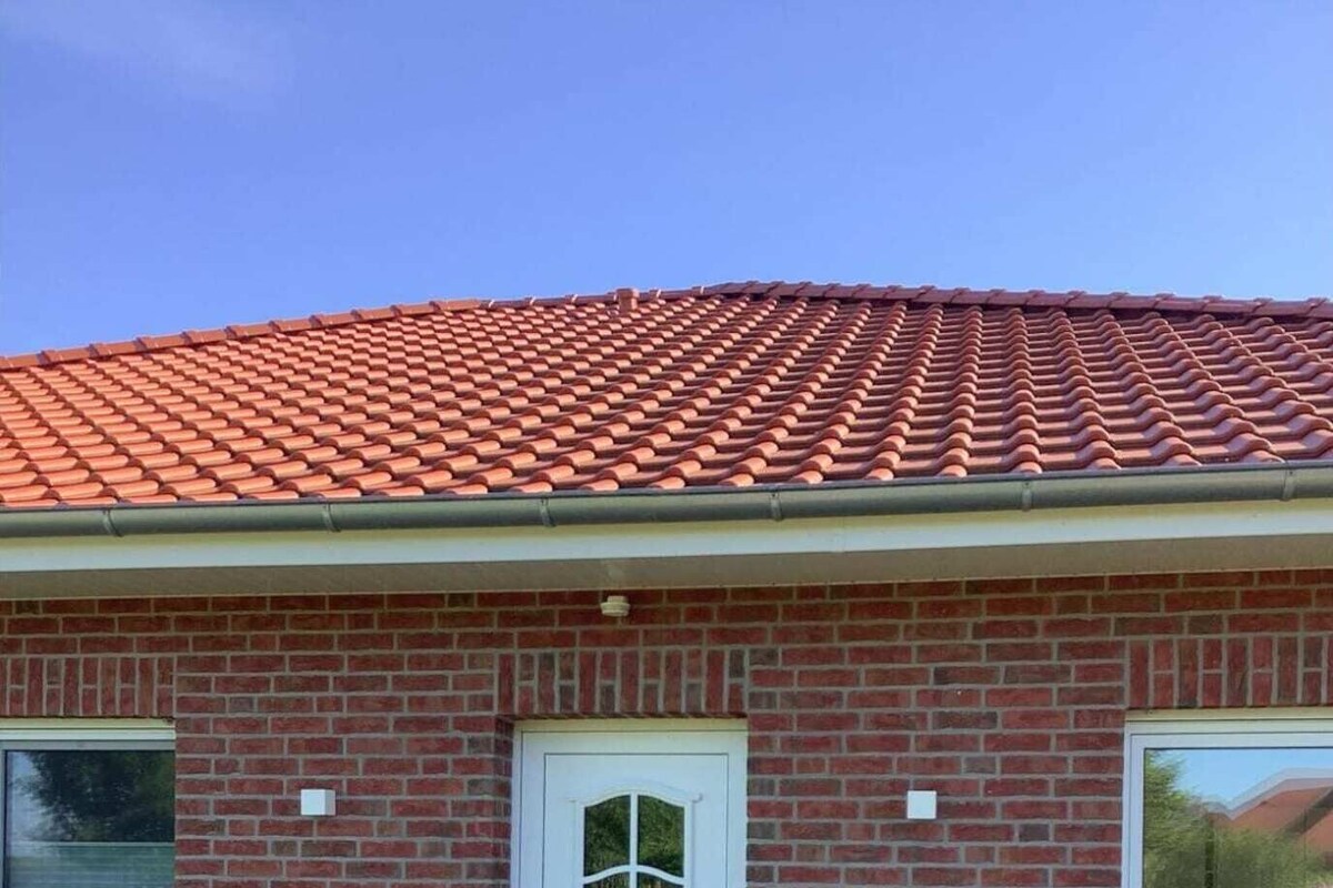 A single-story brick building with a red-tiled roof, a white front door, and a small front porch.