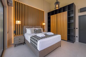 A modern bedroom with a large bed, wooden panel wall, built-in wardrobe, and bedside lamps. - Athena’s Luxury 3-Bedroom Villa with Private Pool & Garden in Koskinou of Rhodes (Koskinou)