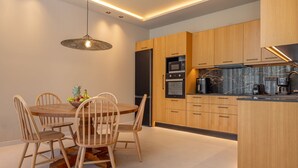 Una cocina moderna con armarios de madera, una isla central y una zona de comedor con una mesa redonda y sillas.