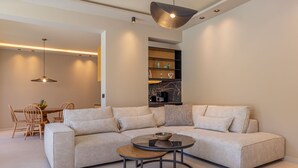 Una sala de estar moderna con un sofá modular, una mesa de centro redonda y un comedor con una mesa y sillas de madera.