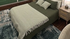 A bedroom with a large bed, green wardrobe, white headboard, and a ceiling light fixture. - Cosy West Kensington Apartment - 3 Min to Tube (London)