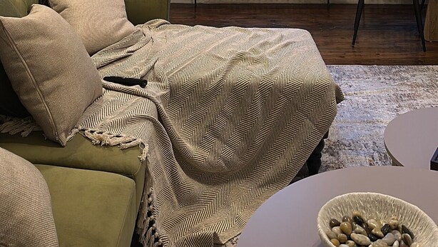 A cozy room with a green sofa, a patterned throw blanket, a side table with a bowl, and a chair. - Cosy West Kensington Apartment - 3 Min to Tube (London)