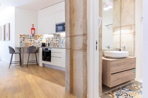 A modern kitchen with white cabinets, a microwave, and a patterned backsplash. - Caldeireiros 95 by LovelyStay (Porto)