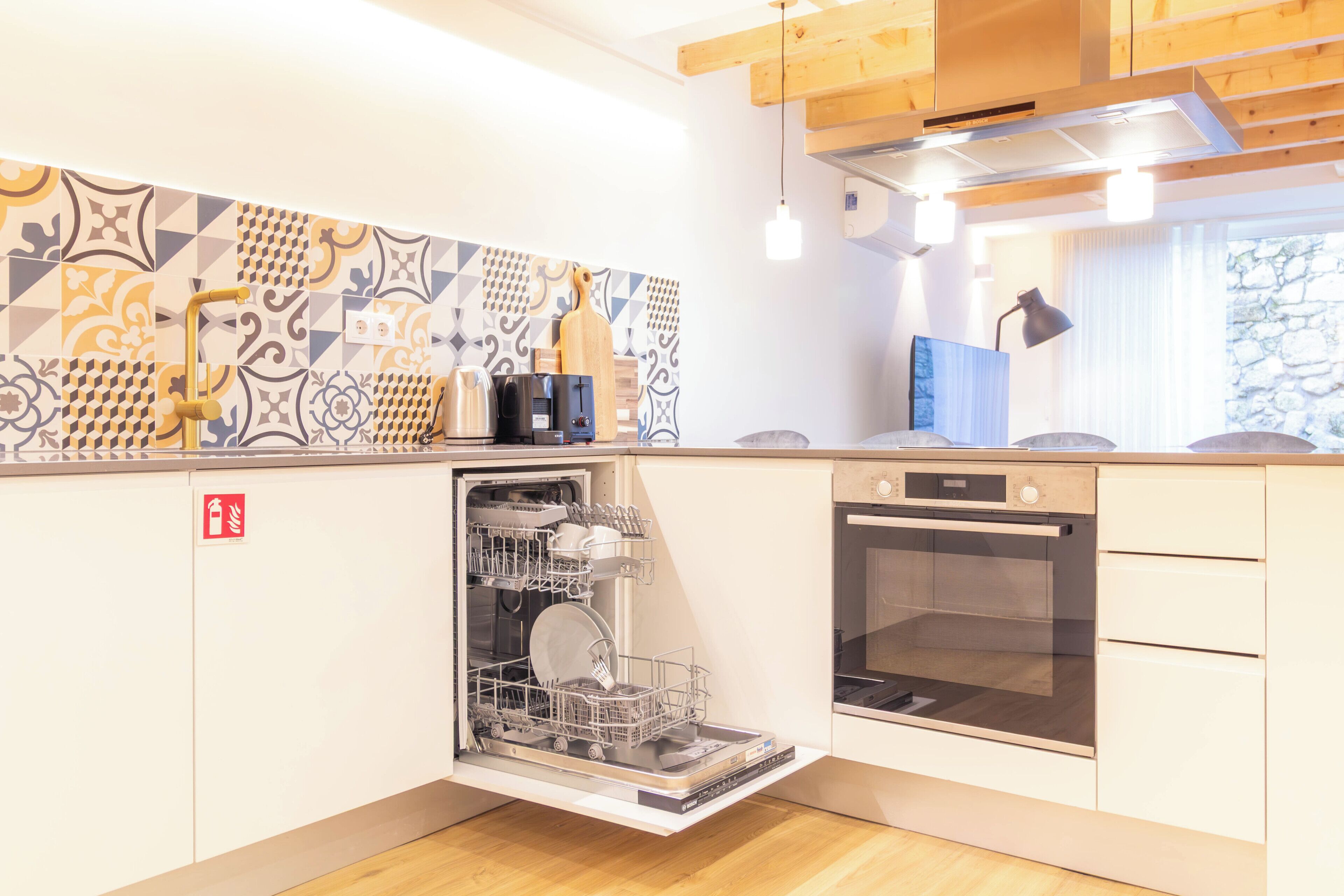 Una cocina moderna con lavavajillas, horno y un salpicadero decorado.
