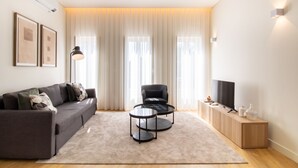 Una sala de estar moderna con un sofá, dos sillones, una mesa de centro, un televisor y un mueble.