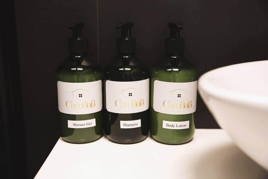 Three bottles of CardiB products: Shower Gel, Shampoo, and Body Lotion, on a white surface.