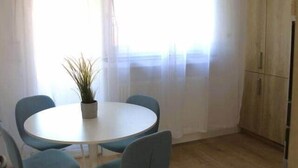 A dining area with a round table and four chairs, a potted plant, and a wooden cabinet. - Beautiful Cosy 2BR Apartment (Luxembourg City)