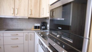 A modern kitchen with stainless steel appliances, wooden cabinets, and a coffee maker on the countertop. - Beautiful Cosy 2BR Apartment (Luxembourg City)