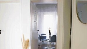 A hallway with wooden flooring, a dining area with chairs and a table, and a door with a mirror. - Beautiful Cosy 2BR Apartment (Luxembourg City)