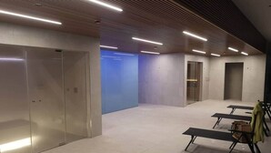 Una habitación amplia, bien iluminada, con piso de baldosas, un banco y un perchero con una chaqueta.