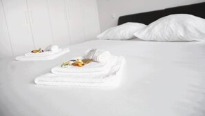 Una habitación de hotel con una cama bien hecha, toallas blancas y un cabecero negro.