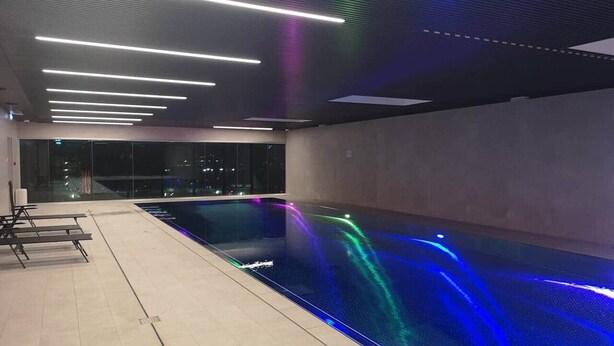Una piscina interior de diseño moderno, con una piscina larga y estrecha y una zona de estar con bancos.