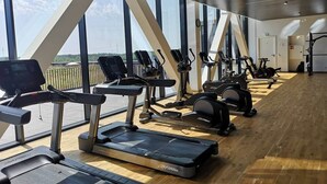 Un gimnasio con cintas de correr, bicicletas estáticas y máquinas elípticas.