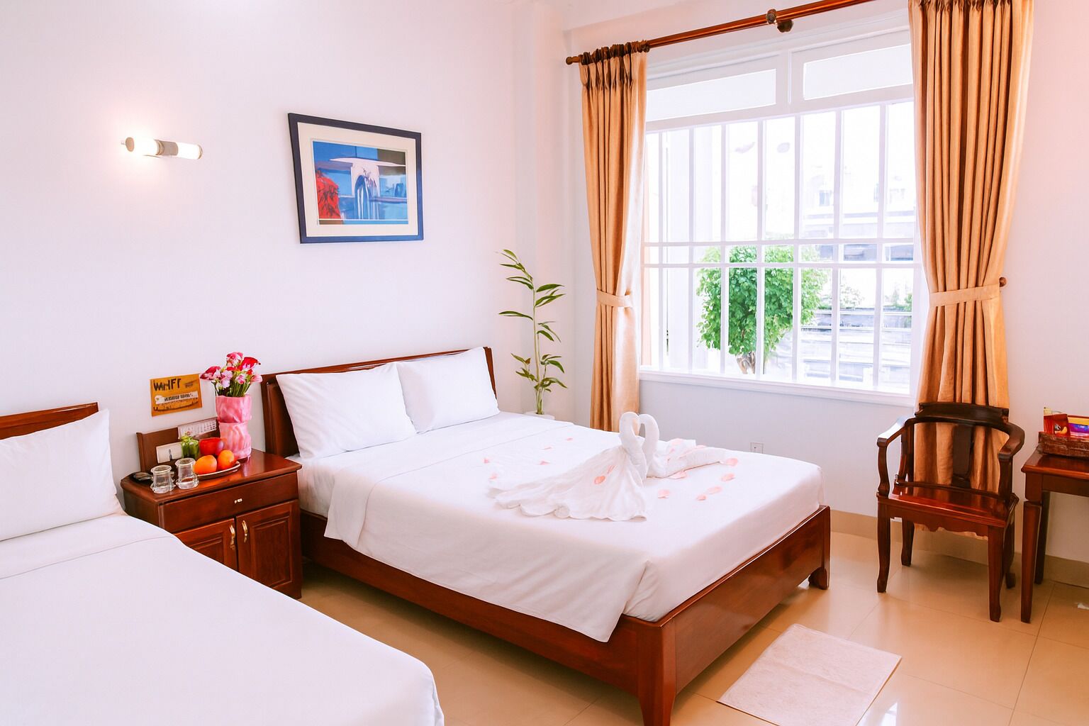 A hotel room with a bed, bedside table, chair, window with curtains, and a wall-mounted picture.