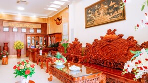 Een hotellobby in traditionele Chinese stijl, met decoratief meubilair, een receptiebalie en een lijstwerk schilderij aan de muur.