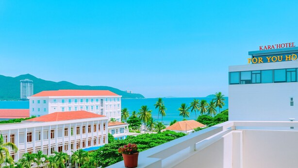 Een hotel genaamd "Kara'Hotel" met uitzicht op zee en palmbomen.