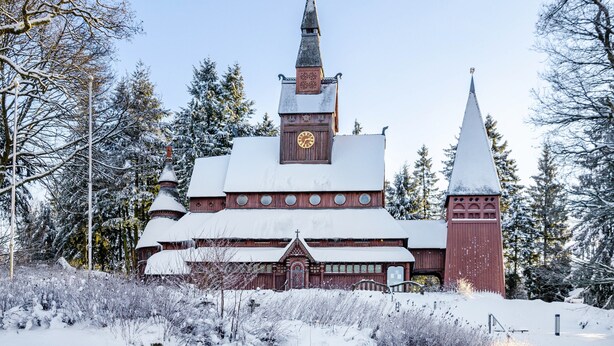 A church with a clock tower and a steeple, surrounded by snow-covered trees. - Apartment "Räuberhöhle" with Balcony and Wi-Fi (Goslar)