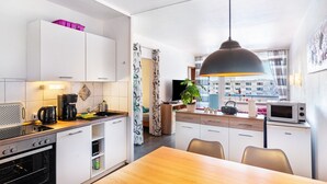 A modern kitchen with a dining area, a microwave, and a television. - Apartment "Räuberhöhle" with Balcony and Wi-Fi (Goslar)