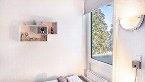 A bedroom with a window, a radiator, a shelf with decorative items, and a bedside lamp. - Apartment "Räuberhöhle" with Balcony and Wi-Fi (Goslar)