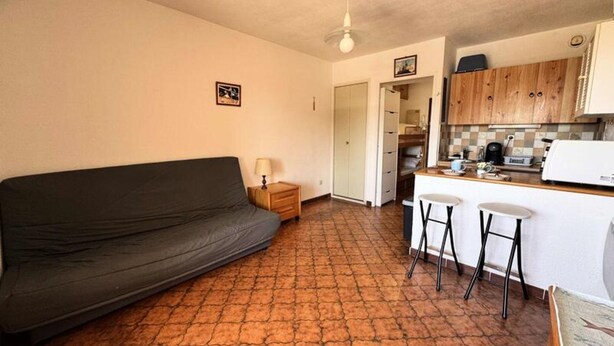 Un espacio habitable compacto con sofá, kitchenette pequeño y zona de comedor.