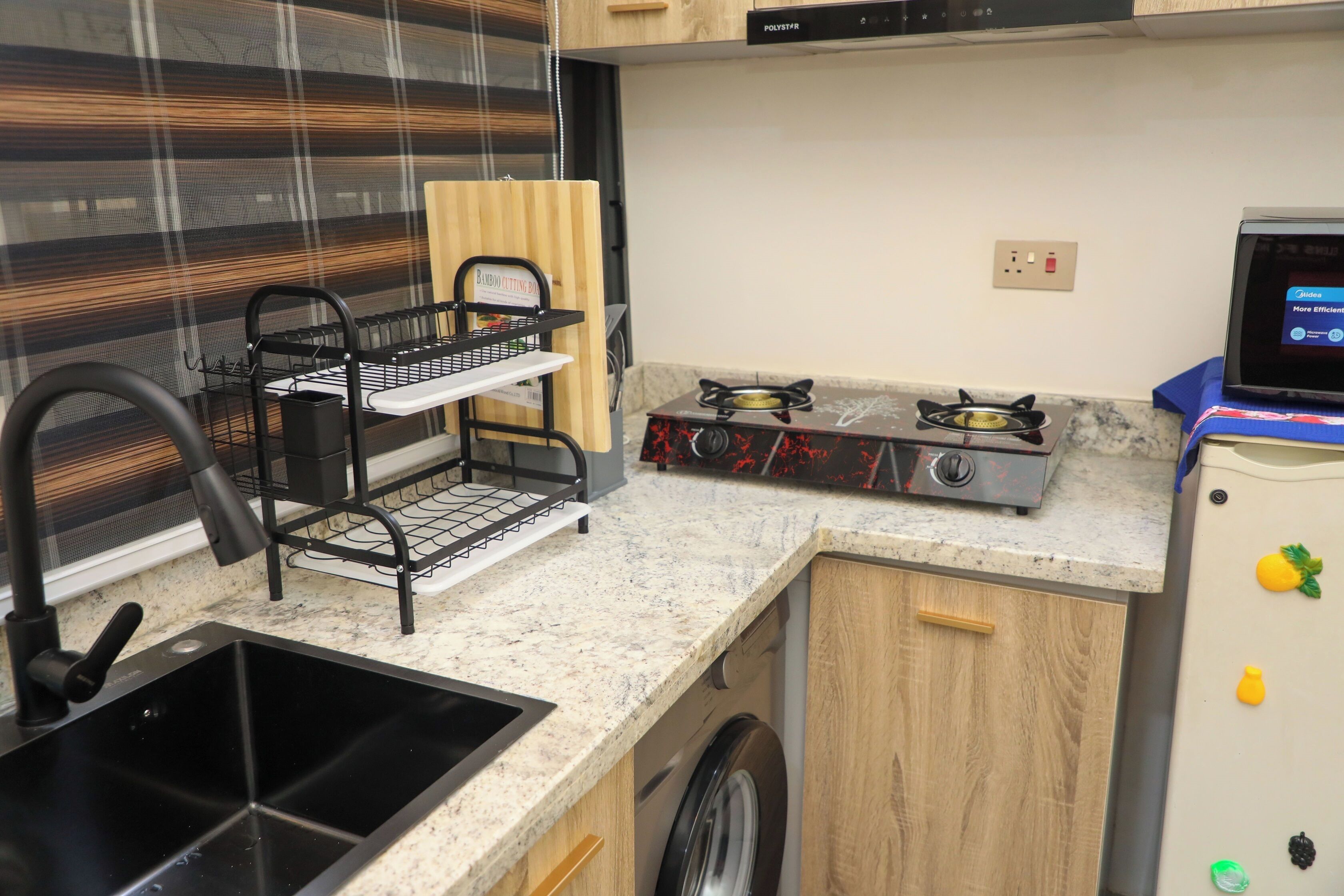 A compact kitchen with a sink, a stove, and a washing machine.