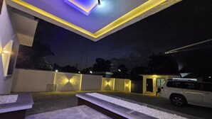 A modern outdoor seating area with a car parked nearby. - ED - Havilah Suites (Abuja)