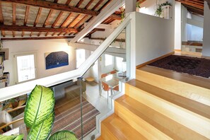A modern interior with a wooden staircase, a dining area, and a view of the outdoors. - Biennial Terrace (Venezia)