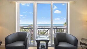 A room with two black leather chairs, a glass-top table, and a view of the ocean through large sliding glass doors. - Unforgettable Luxury at Hyatt Clearwater Beach! (Clearwater Beach)