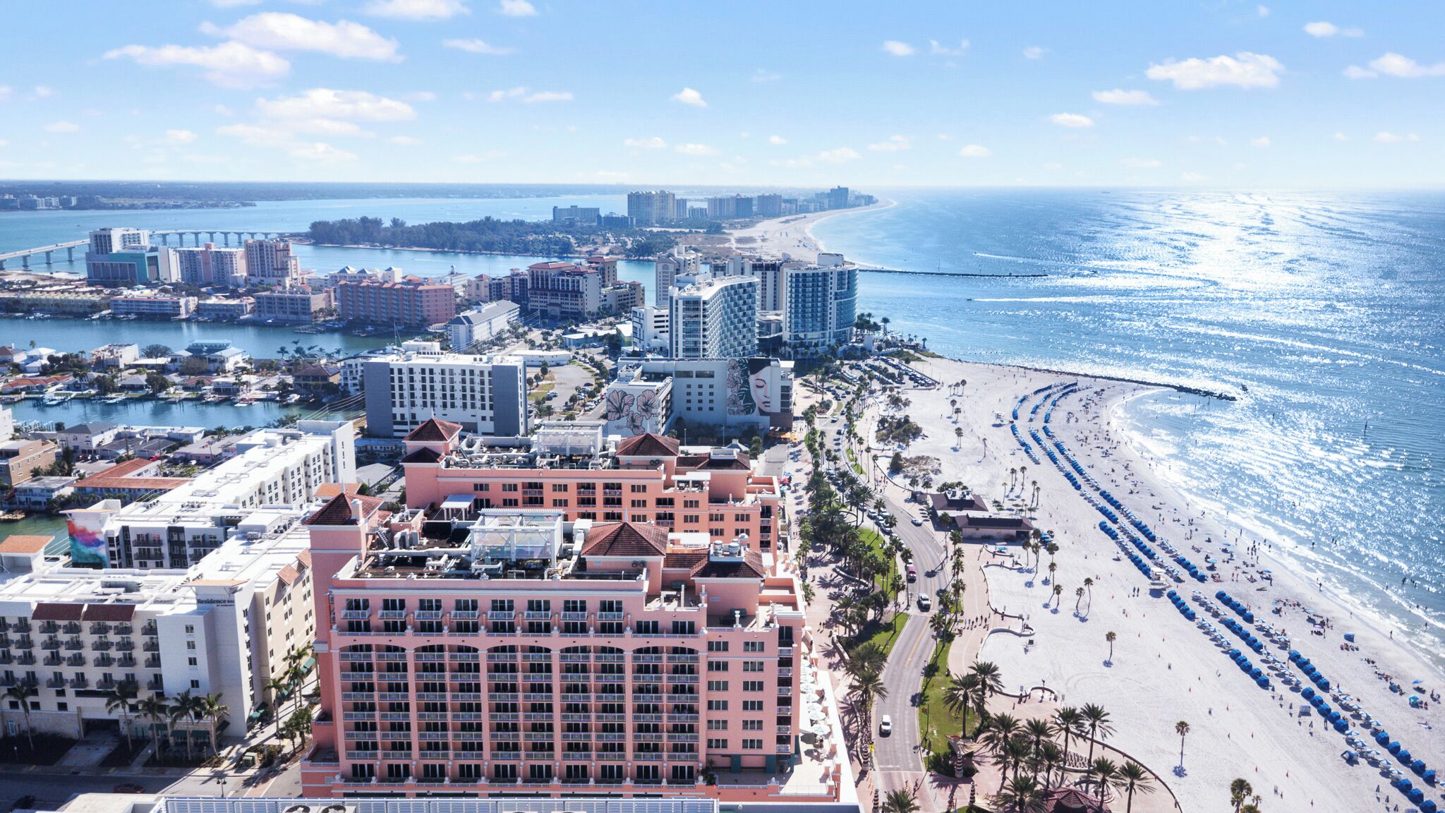 A coastal hotel with multiple floors, a beachside location, and a view of the ocean.