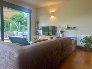 Un salon moderne avec un grand canapé, un téléviseur à écran plat et un coin repas comprenant une table et des chaises.